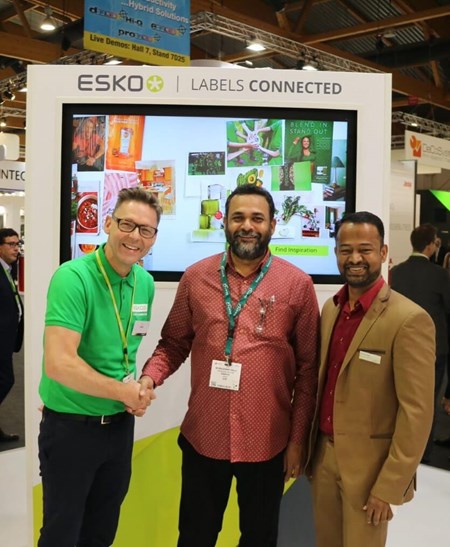 three men in front of the esko booth at a packaging event