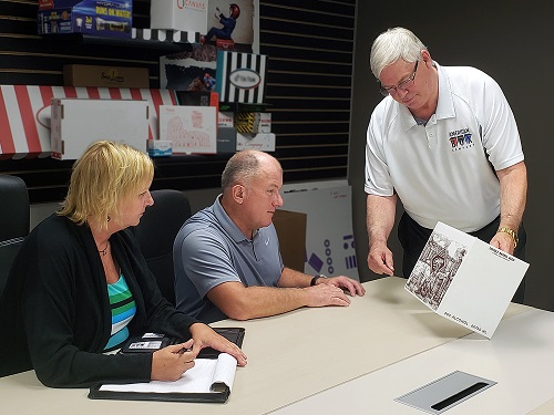 three people at a table looking at a box