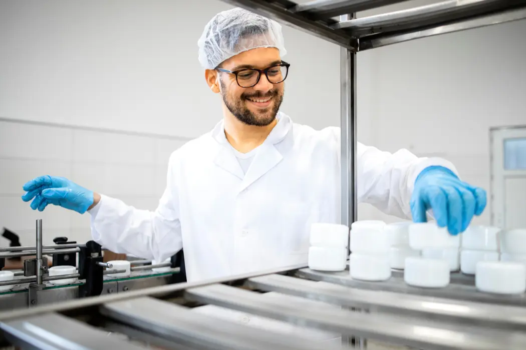 A man in glasses, a lab coat and a cap works in the laboratory