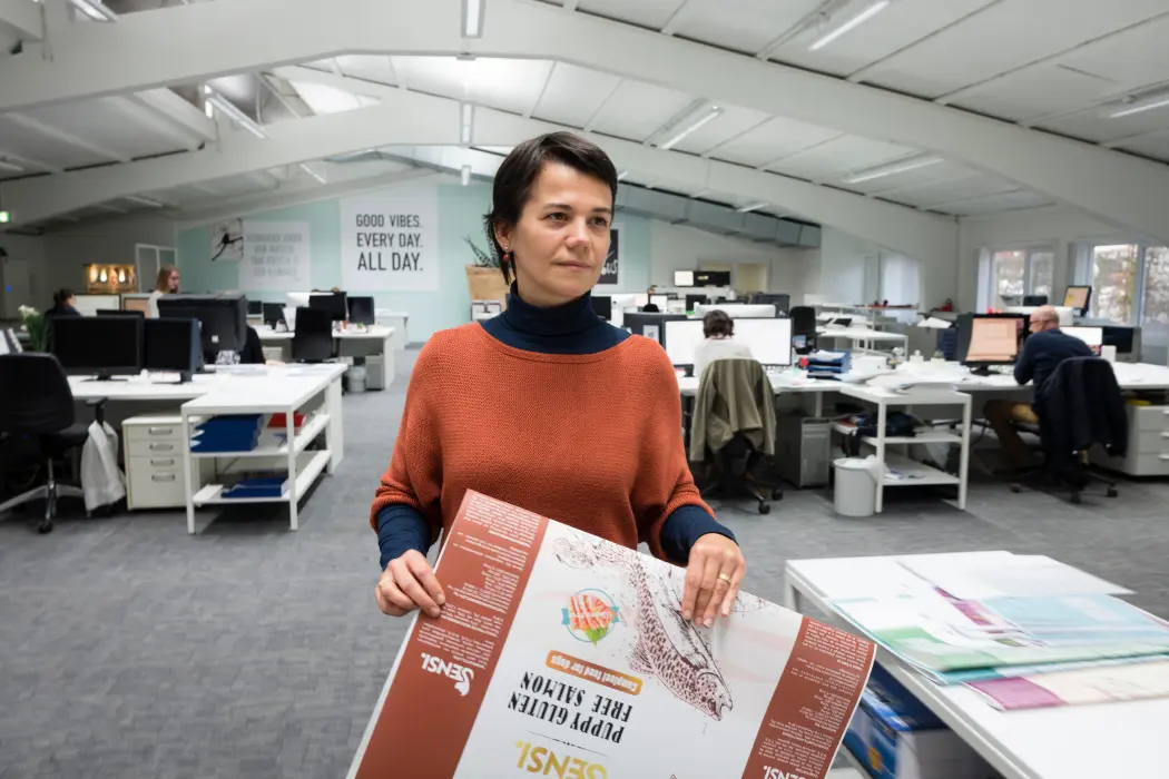 Woman standing in the office holding a poster